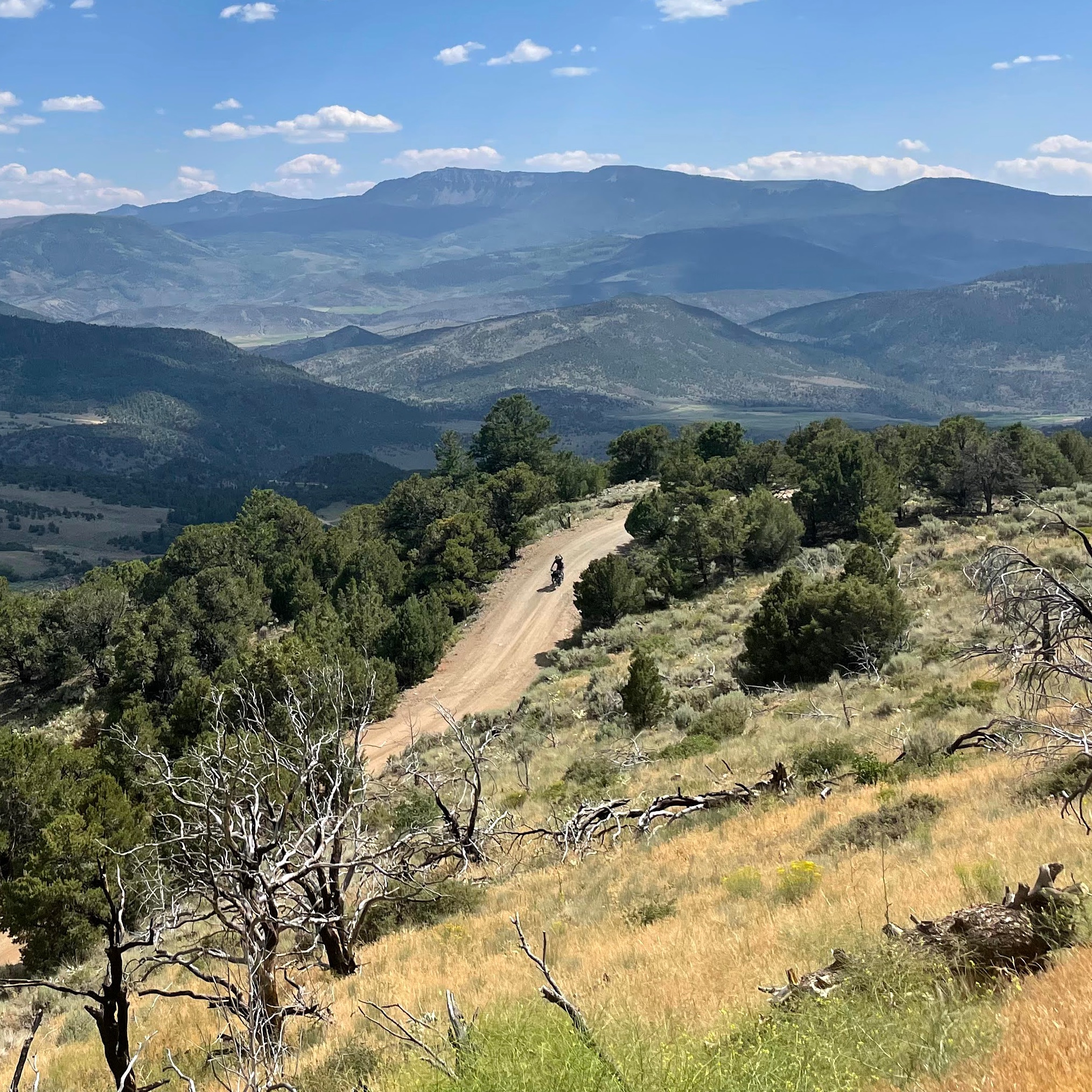 Landscape image of a gravel road with a cyclist descending