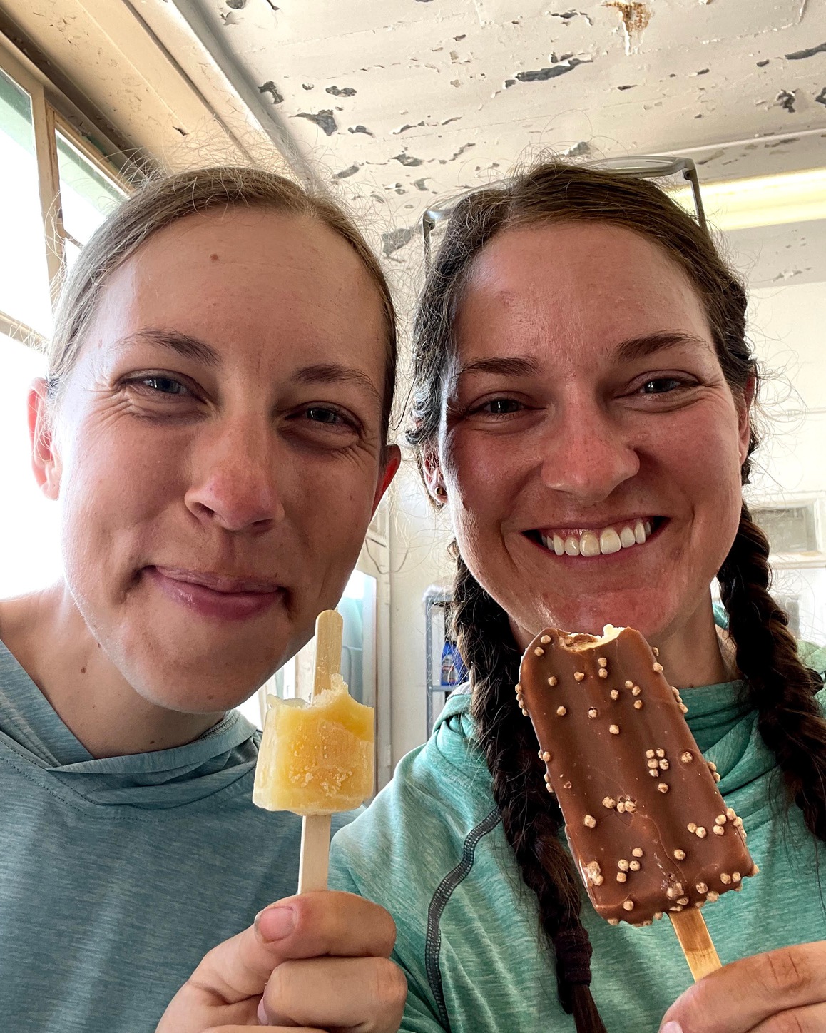 Alyssa Hursh eaching an ice cream popsicle with her friend Stephanie